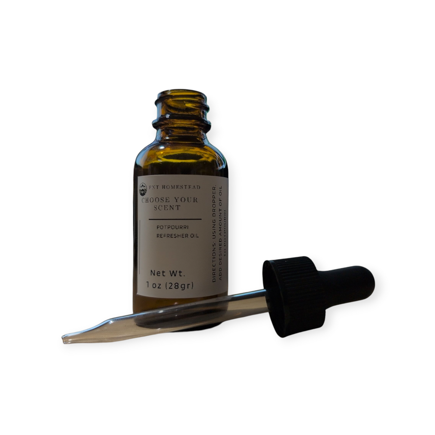 This is a clean product photograph of a potpourri refresher oil, isolated on a plain white background.
An open, 1 oz. amber glass bottle stands upright. Its white label is clearly legible and reads "FNT HOMESTEAD," "CHOOSE YOUR SCENT," and "POTPOURRI REFRESHER OIL."
In front of the bottle, the black dropper top lies on its side, with the clear glass pipette extending horizontally across the frame. The image is brightly lit, showcasing the product and its components without any distractions.