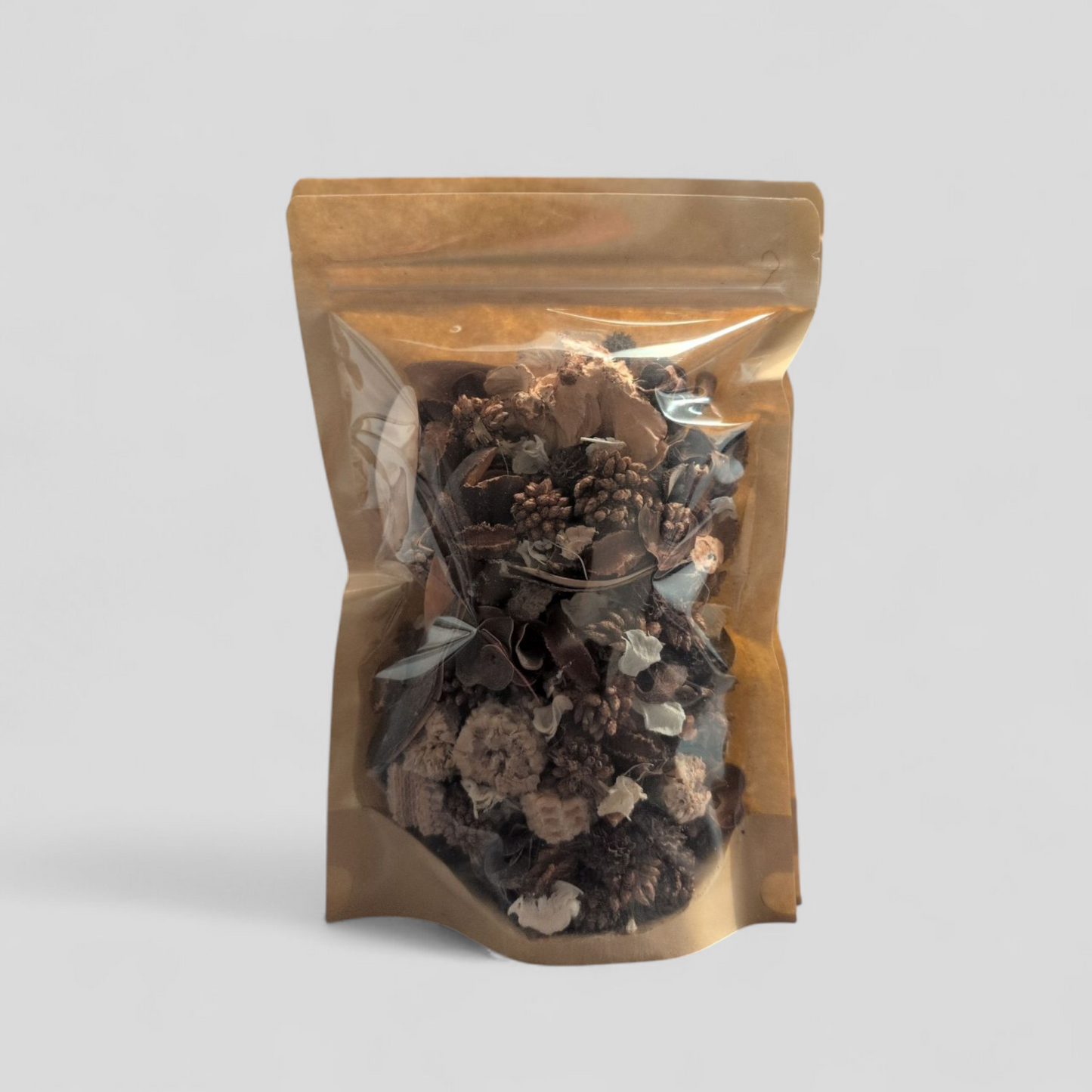A stand-up resealable pouch with a brown kraft paper back and a clear front, filled with brown and white potpourri, against a light gray background.