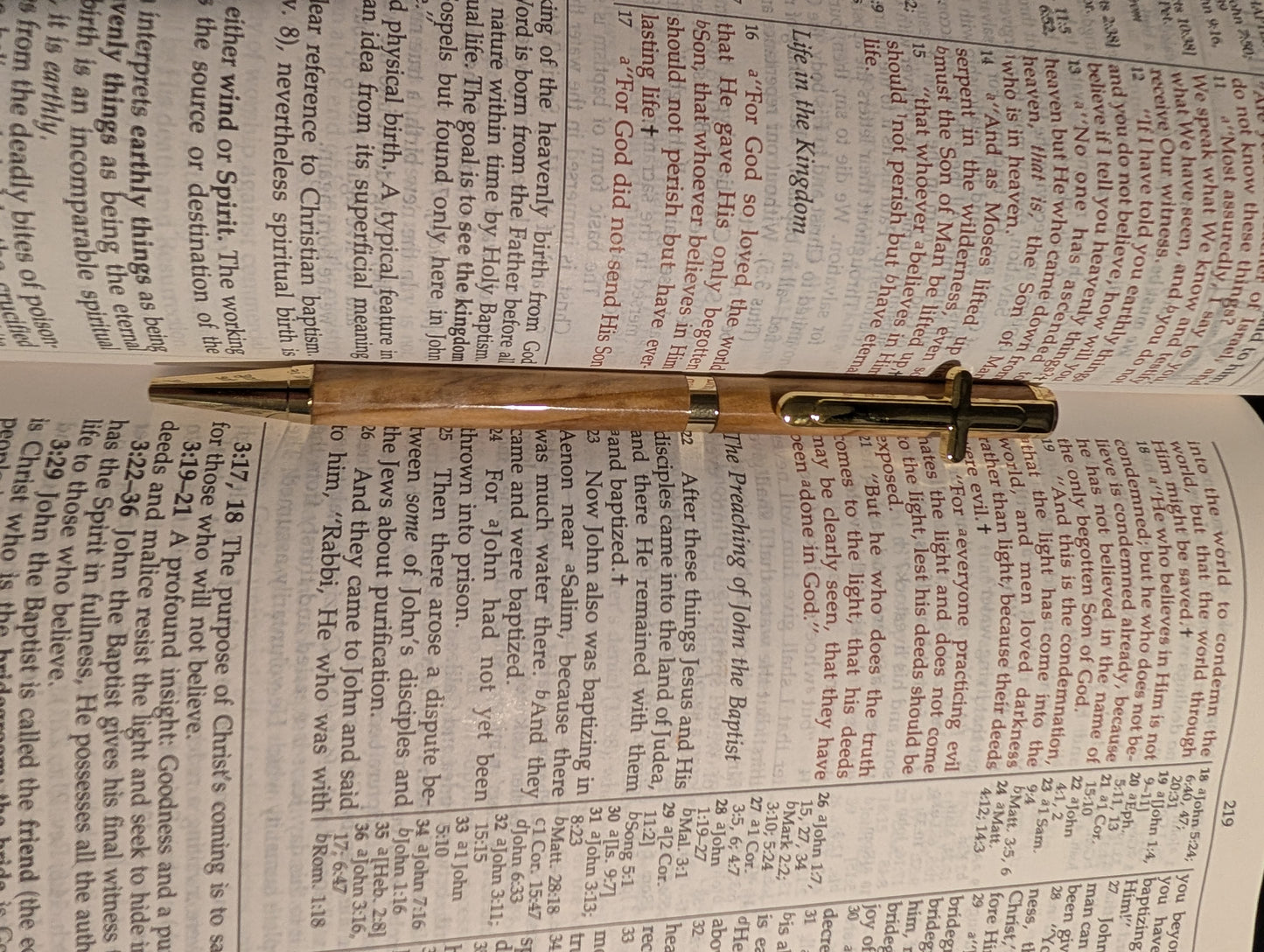 Olivewood pen with gold cross clip on a bible.