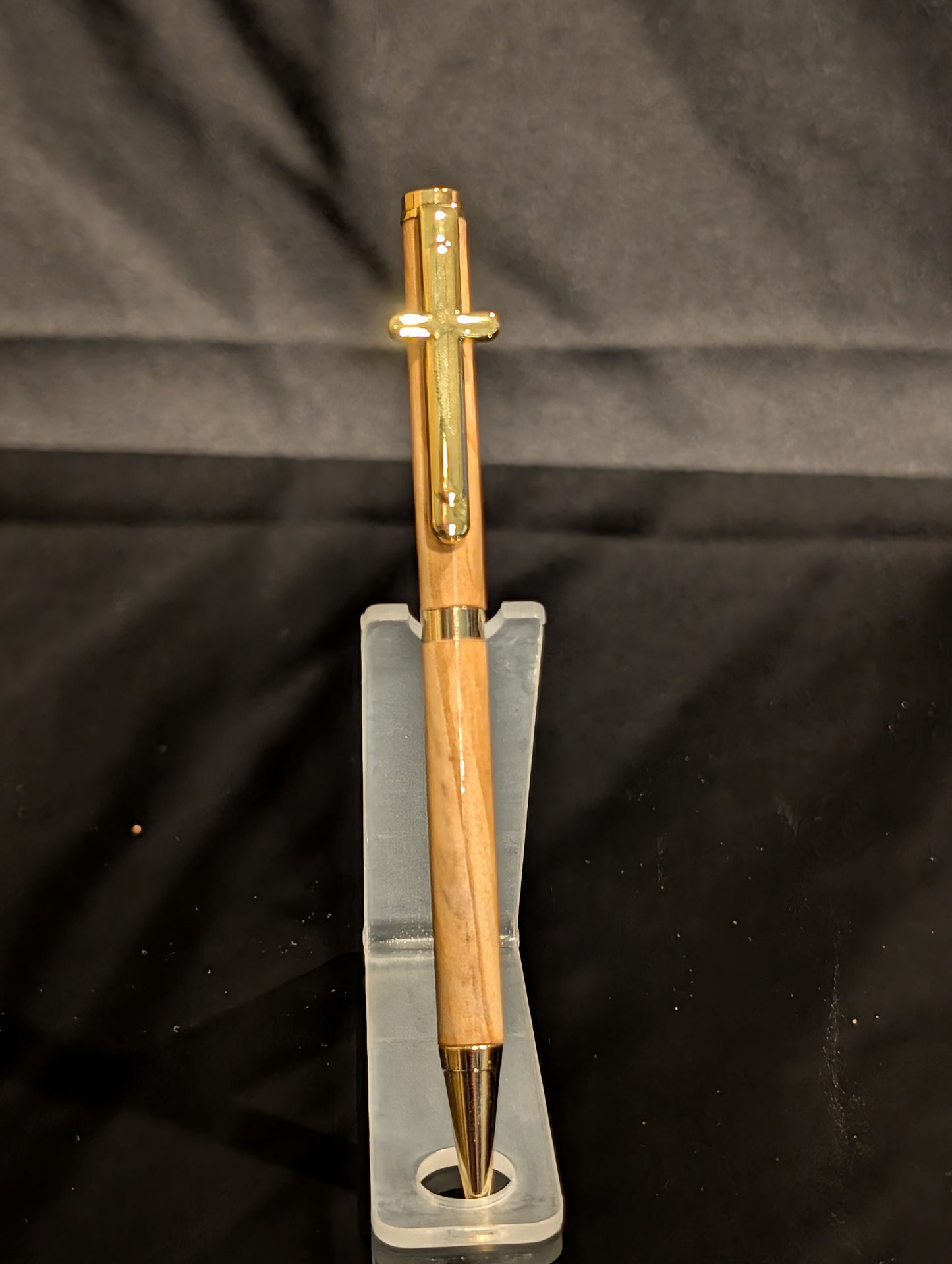 Gold pen on a clear stand against a black background